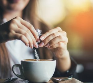 donna inserisce dolcificanti nel cappuccino