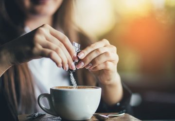 donna inserisce dolcificanti nel cappuccino