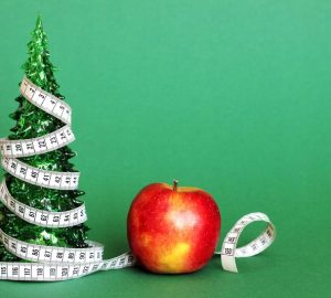 dieta dopo le feste, albero di natale decorato con un metro, accanto una mela rossa