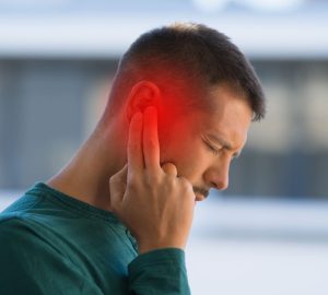 Acufene, ragazzo spinge dita su orecchio dolorante ed evidenziato di rosso