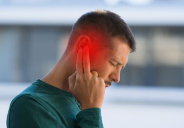 Acufene, ragazzo spinge dita su orecchio dolorante ed evidenziato di rosso
