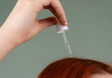 La dermatite seborroica può colpire viso, cuoio capelluto e corpo: Primo piano di una mano che applica siero per capelli su…
